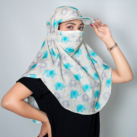 Woman wearing a patterned cap type scarf with elephants and a plain cap on a light gray background