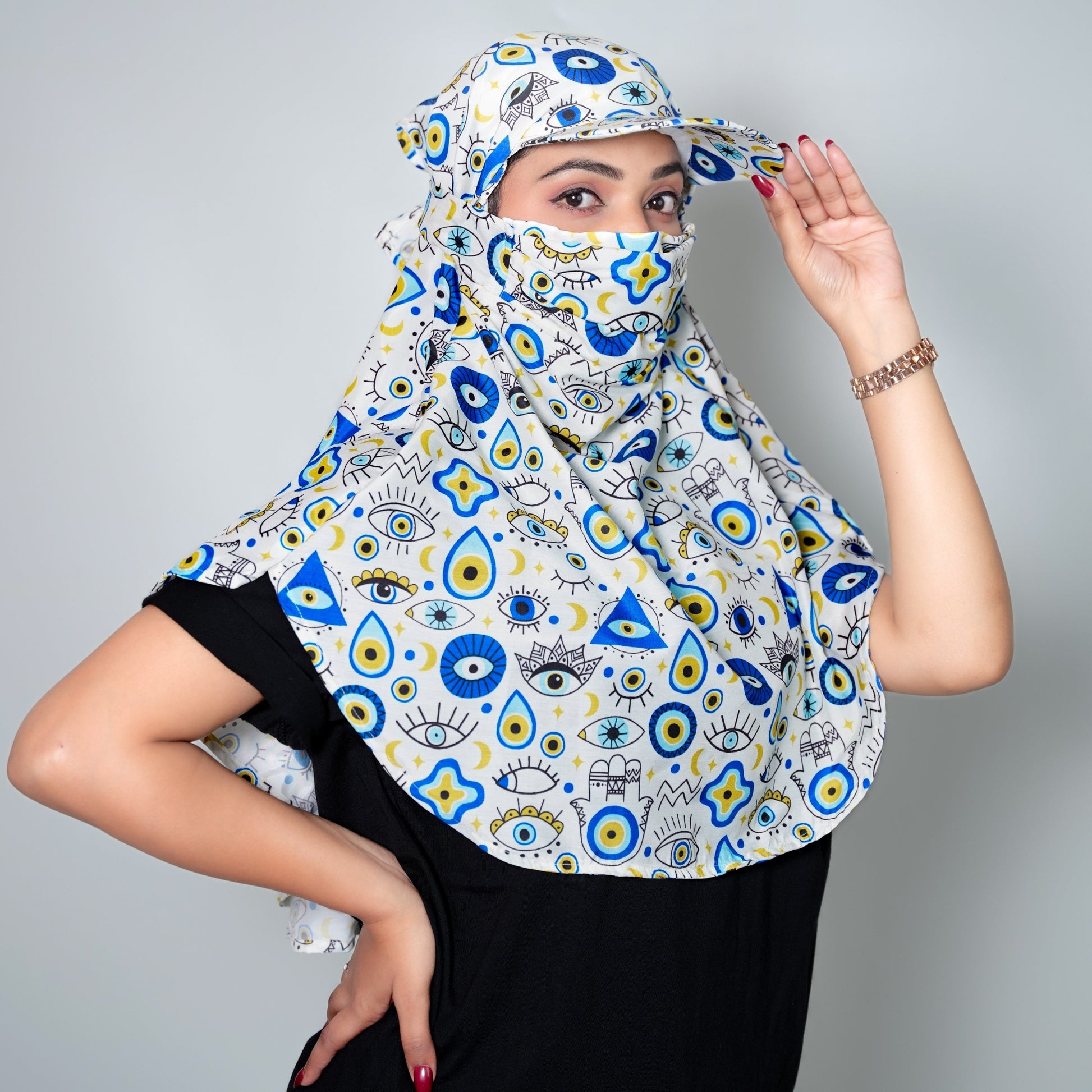 Woman wearing a patterned headscarf with blue, yellow, and white designs on a gray background