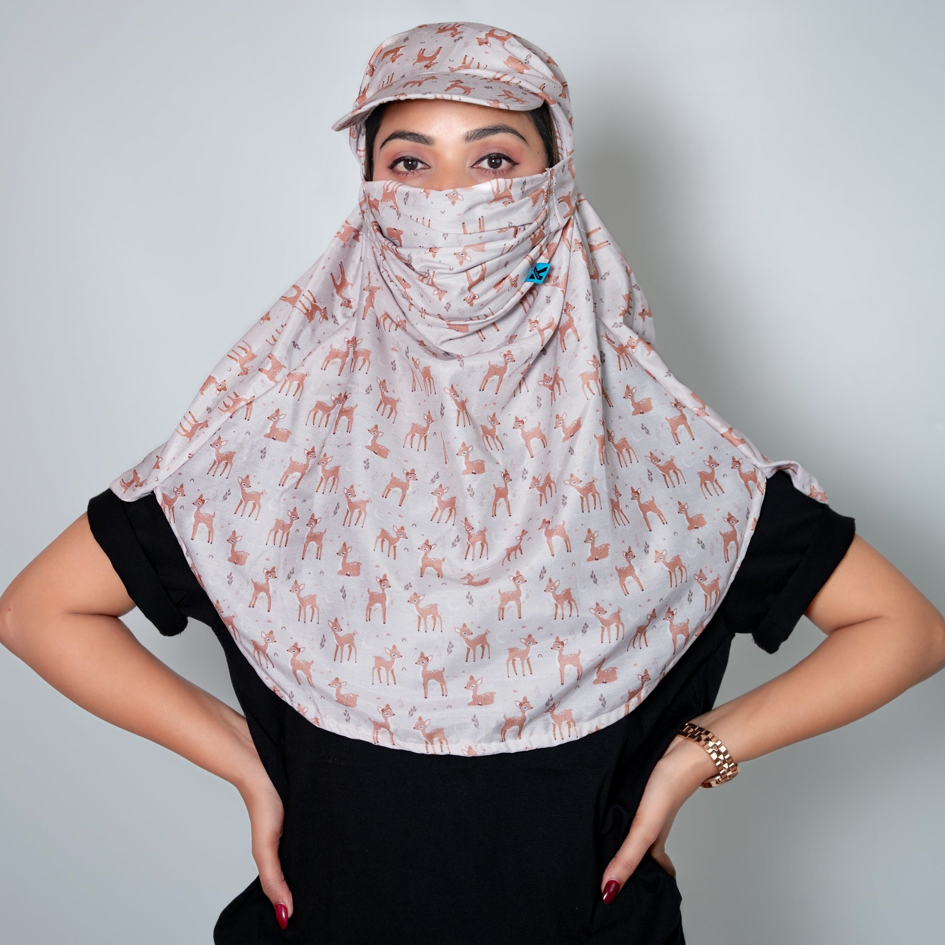 Person wearing a patterned headscarf and cap against a plain background