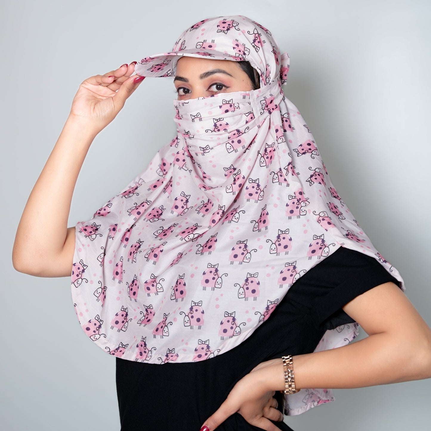 Person wearing a floral-patterned headscarf and cap on a plain background