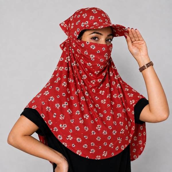 A woman wearing a red sun protection headscarf with a white floral pattern, a matching sun hat, and a face veil, posing against a neutral gray background.