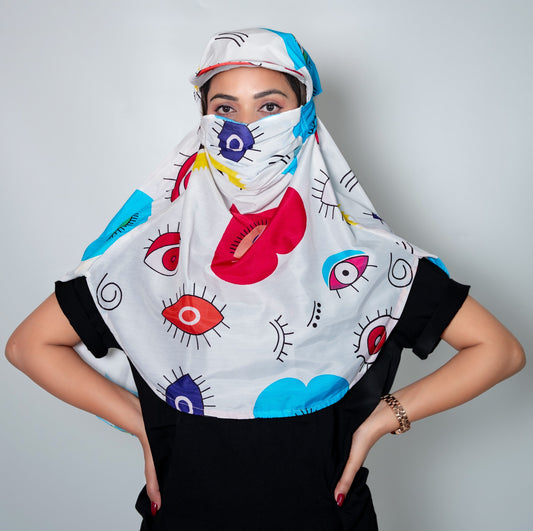Person wearing a colorful headscarf with eye designs on a plain background