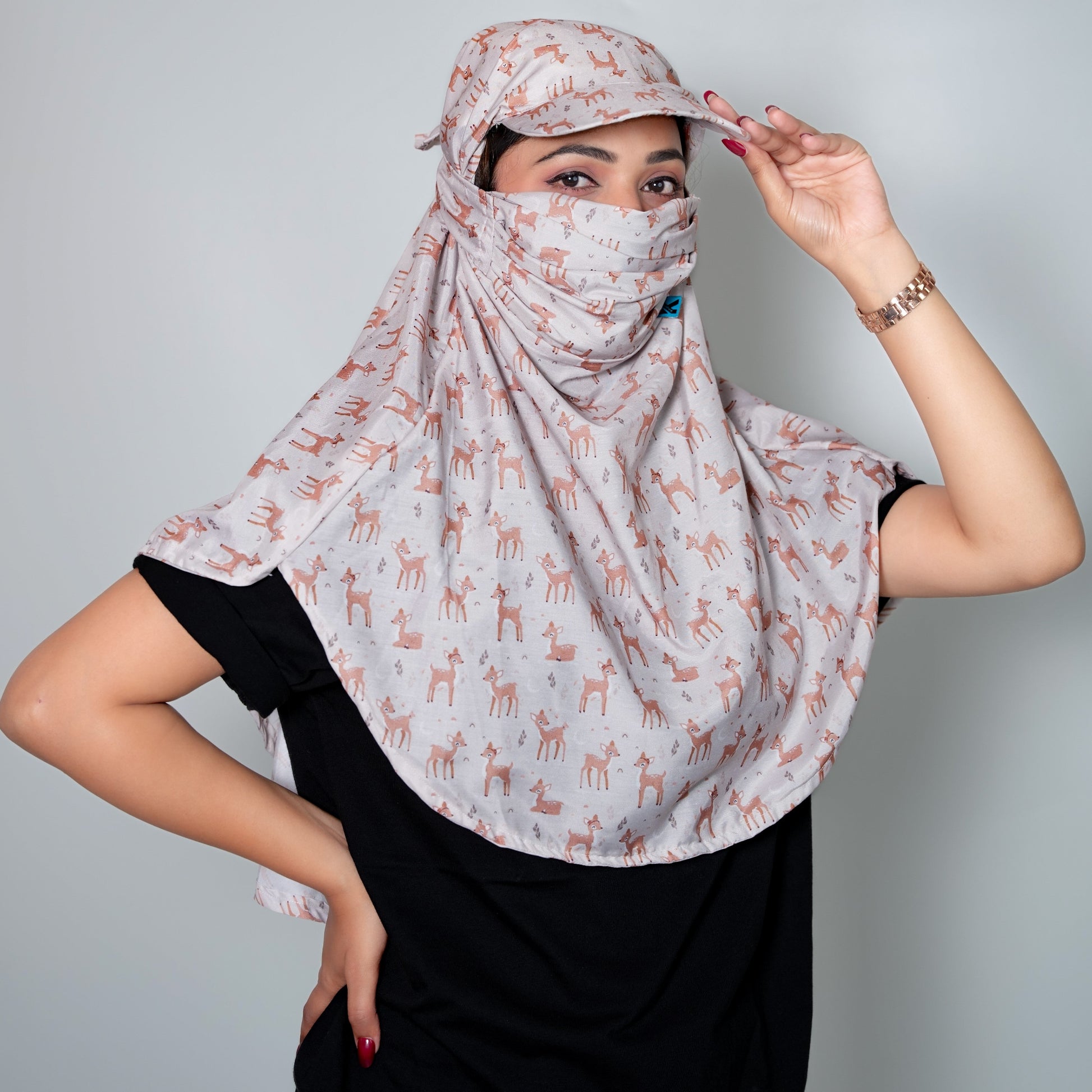 Woman wearing a patterned headscarf and face mask against a plain background