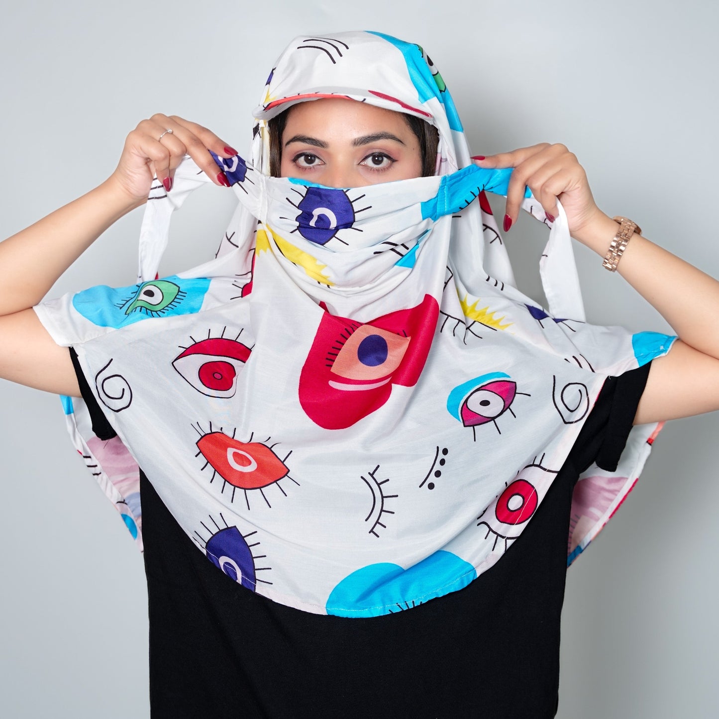 Person wearing a colorful headscarf with eye designs against a plain background