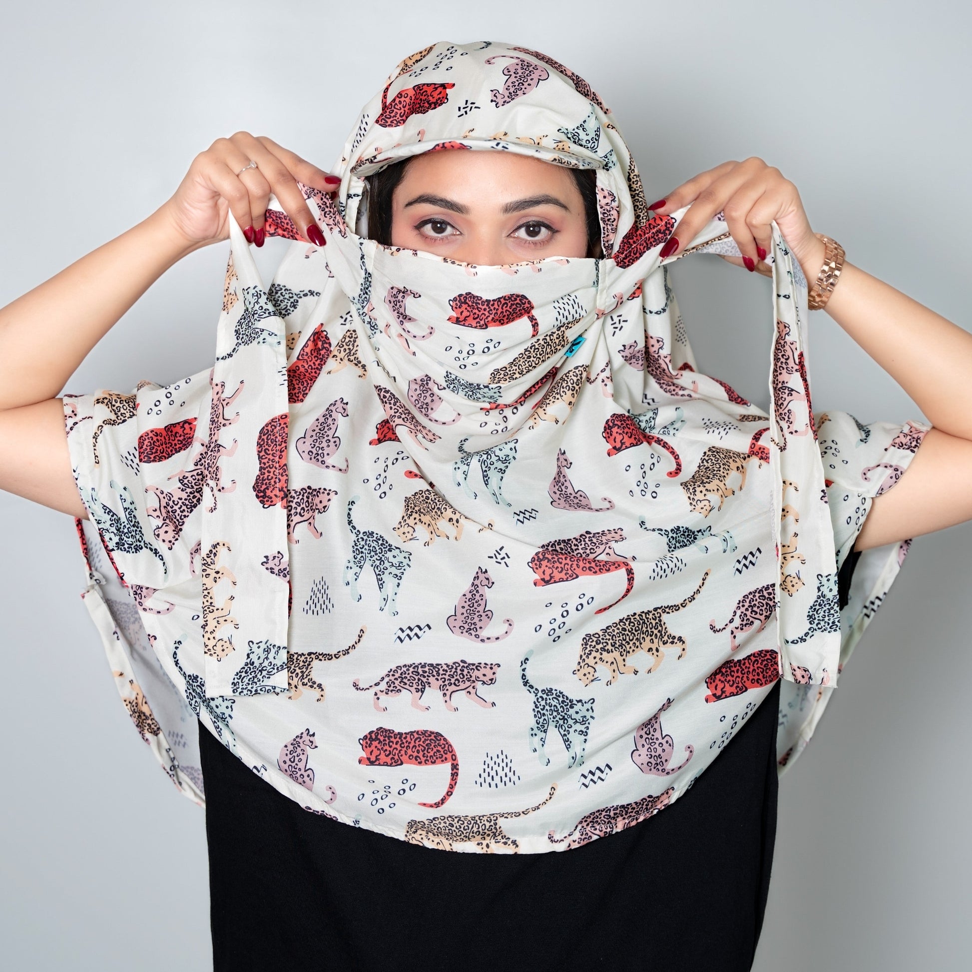 Woman wearing a patterned cap scarf with red and black designs on a plain background