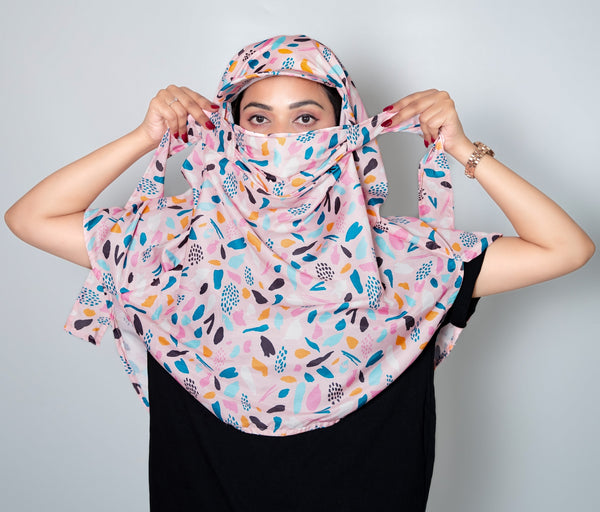 Woman wearing a colorful patterned headscarf against a plain background