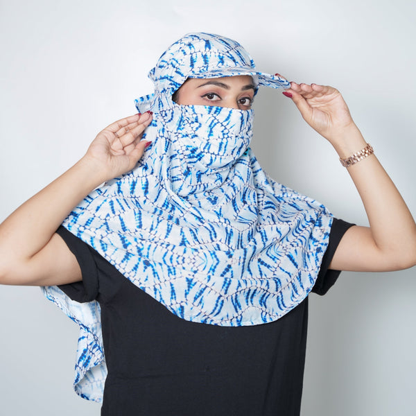 Person wearing a blue and white patterned headscarf against a plain background