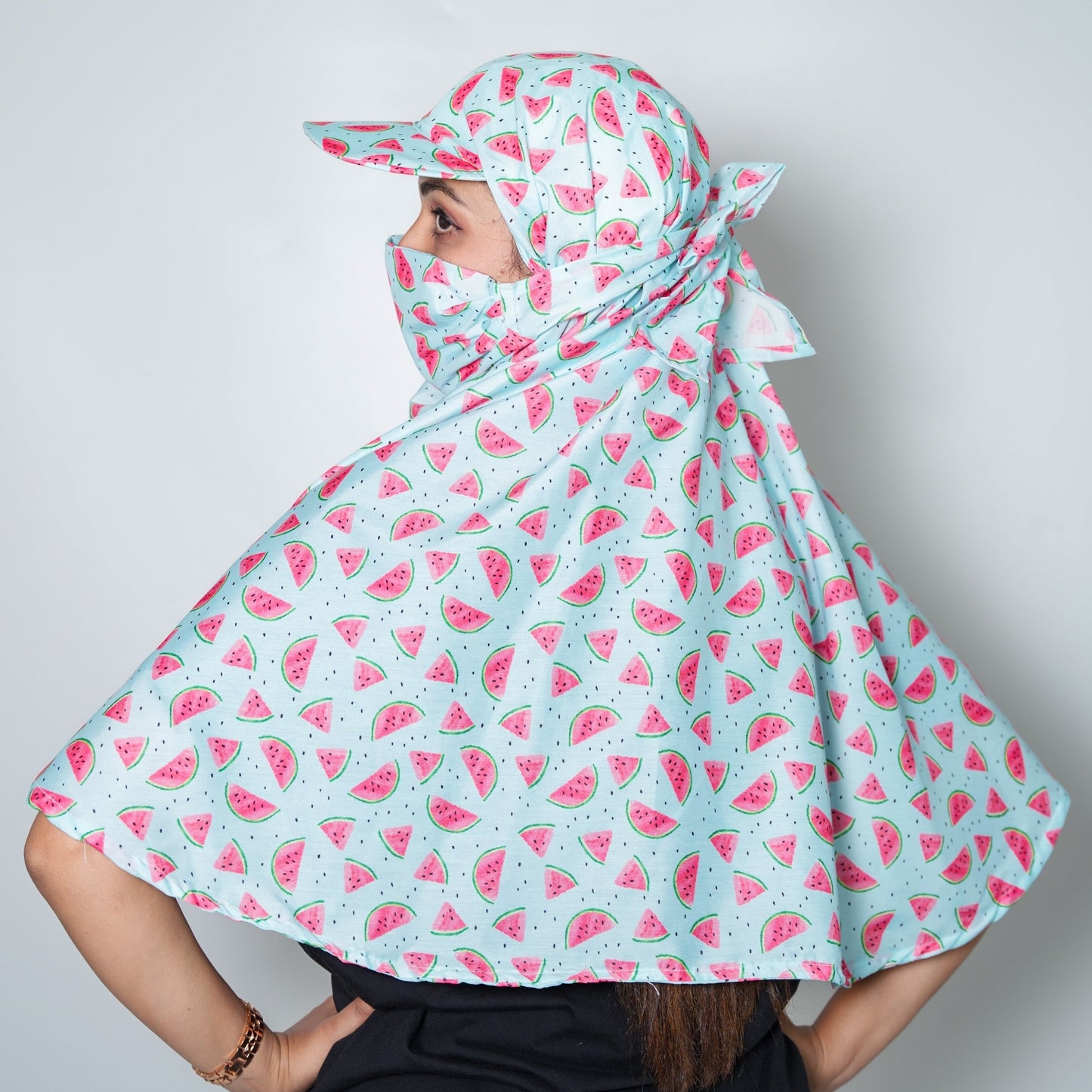 Women wearing a light blue cap scarf with pink watermelon patterns on a plain background