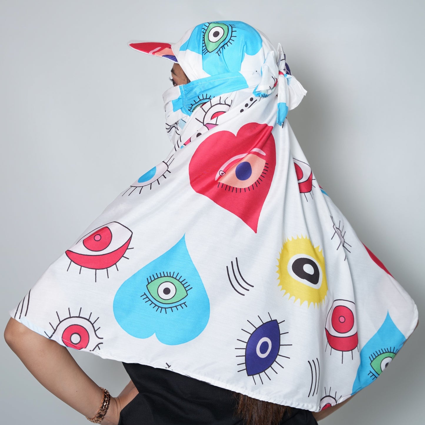 Person wearing a colorful, patterned hooded garment with abstract designs on a plain background
