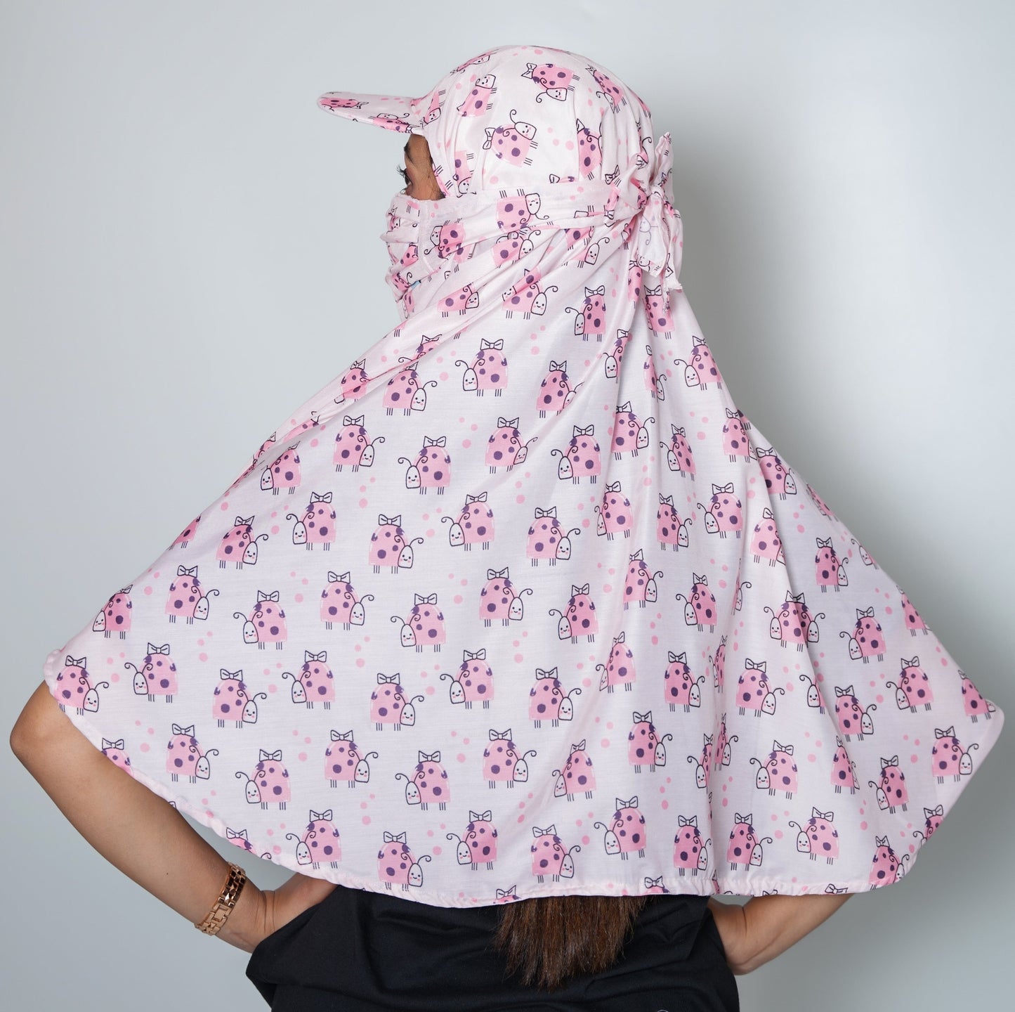 Person wearing a white hijab with pink floral patterns on a plain background