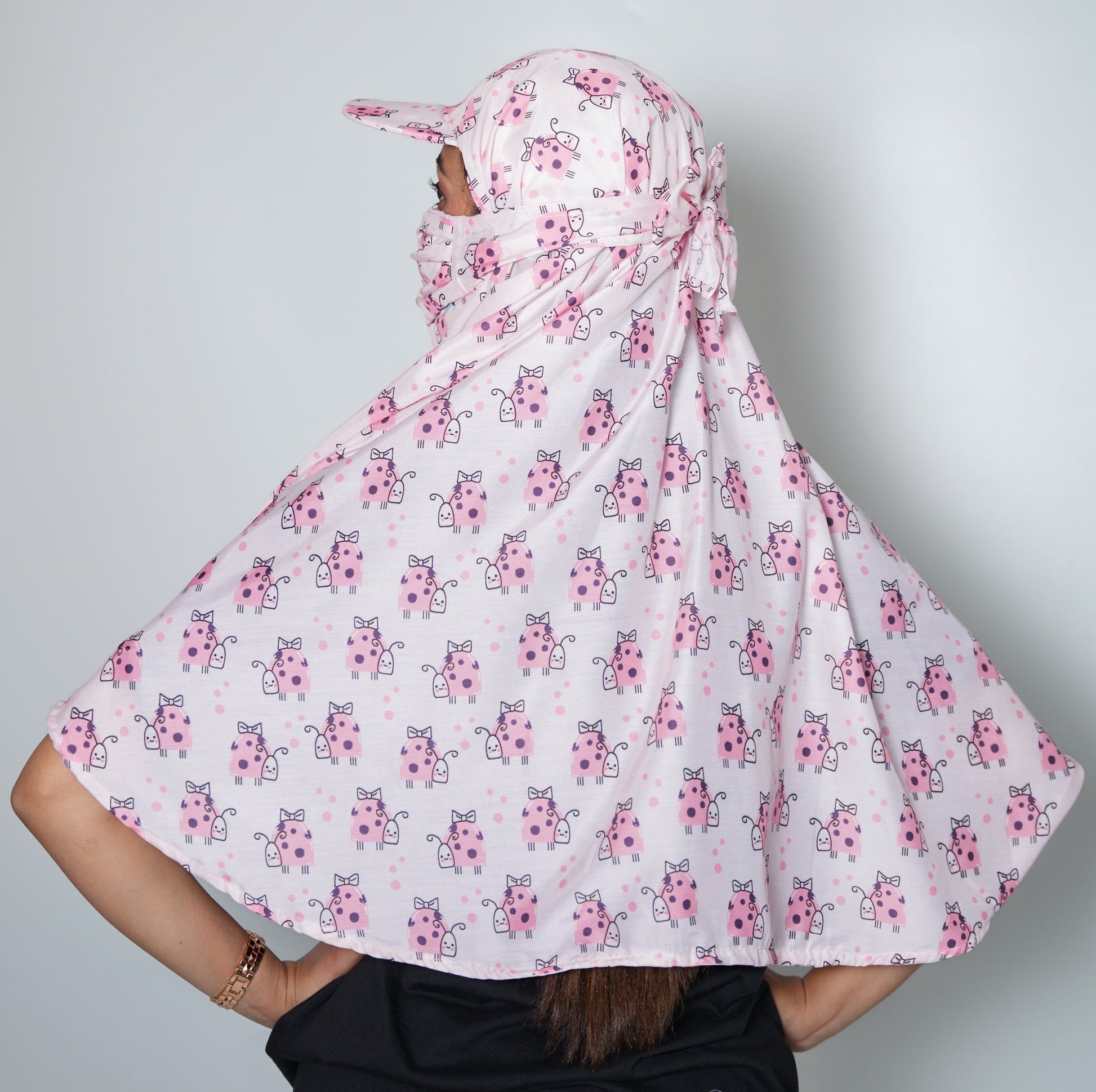 Person wearing a white hijab with pink floral patterns on a plain background