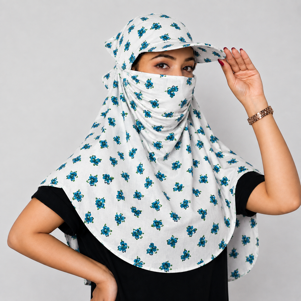 A woman wearing a white head scarf-style face veil with a blue floral pattern, paired with a matching cap and a black top, posing against a light gray background.
