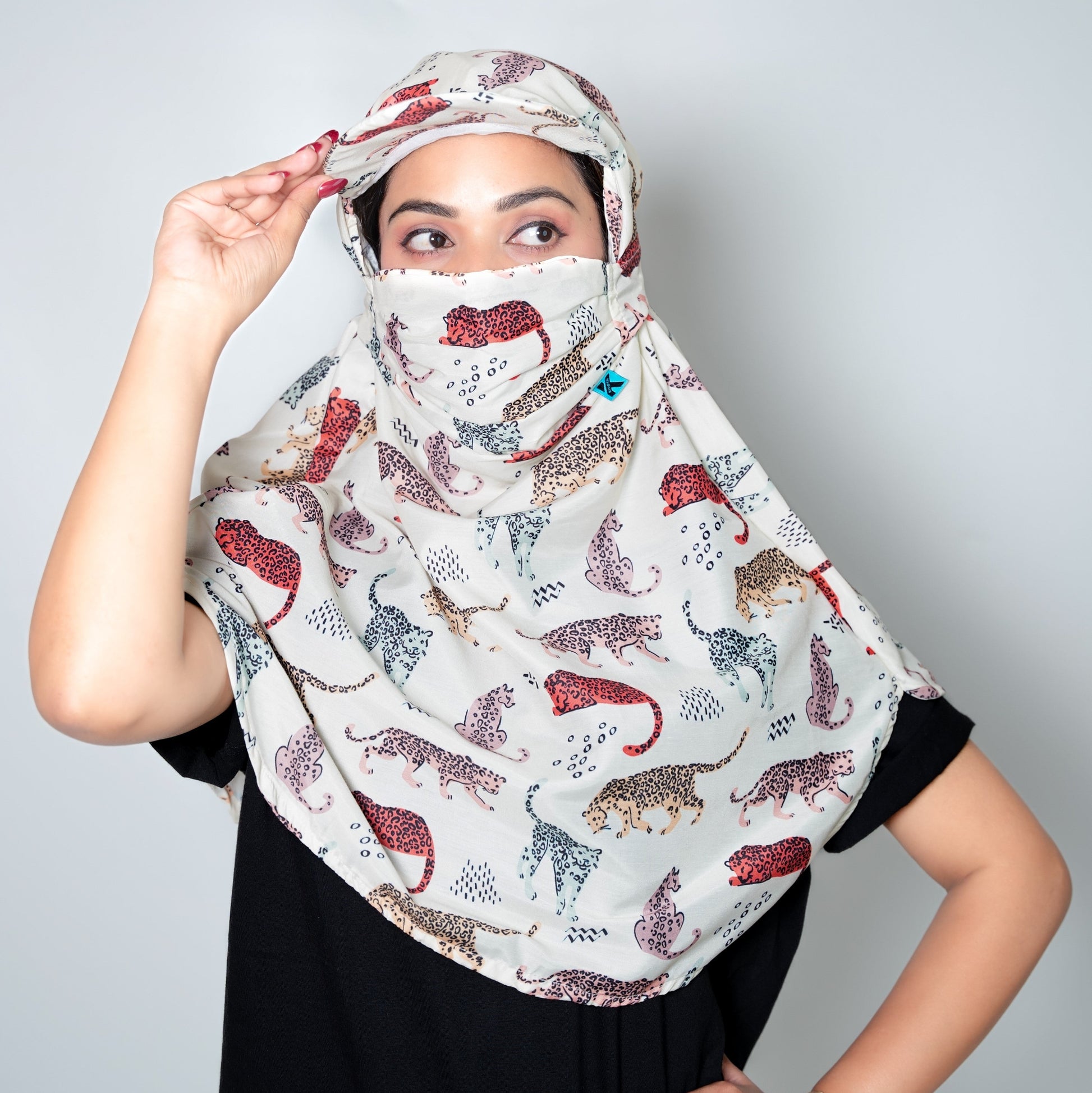 Woman wearing a patterned headscarf and face cover against a plain background