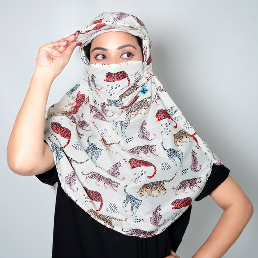 Woman wearing a patterned headscarf and face cover against a plain background