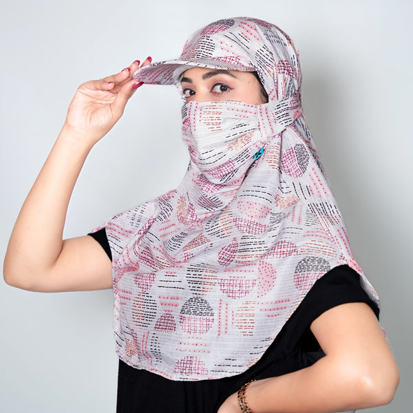 Woman wearing a patterned headscarf and cap against a plain background