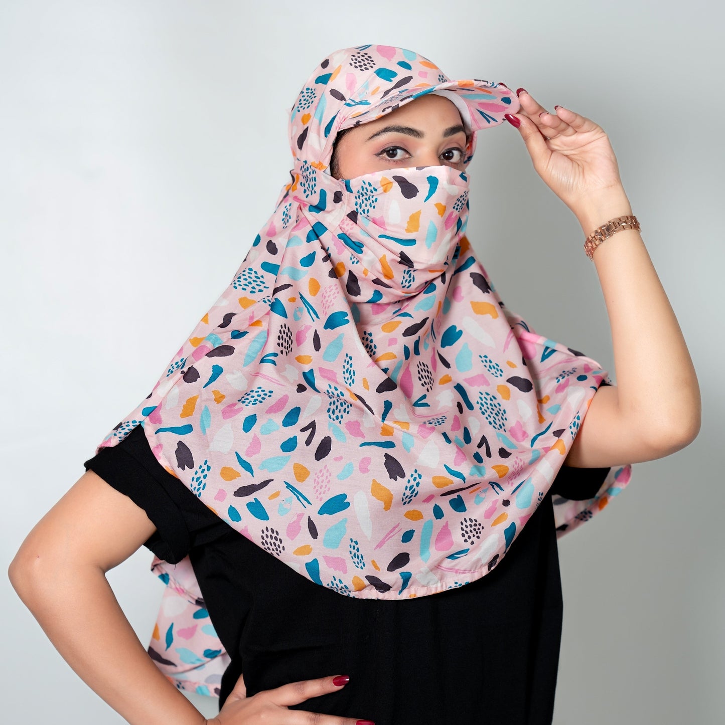 Woman wearing a colorful scarf and cap against a plain background