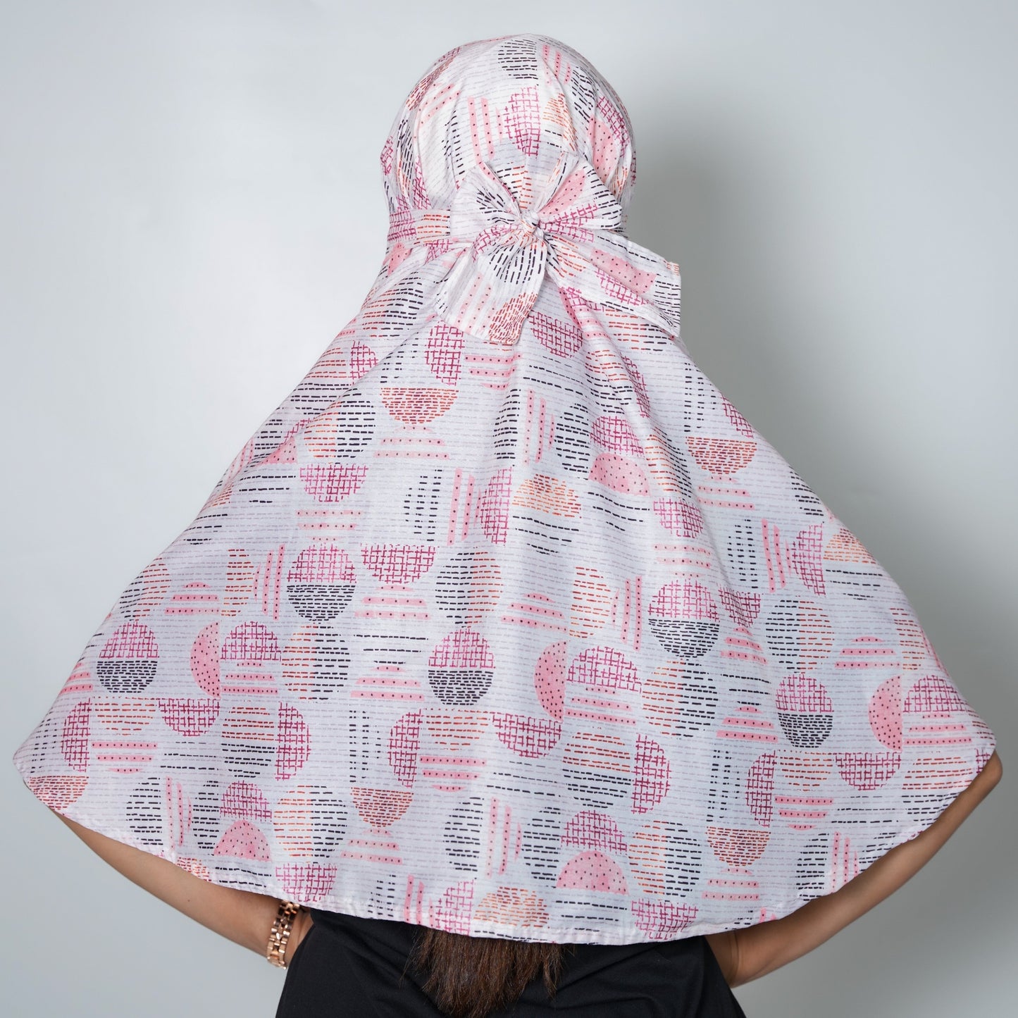 Person wearing a patterned headscarf on a plain background
