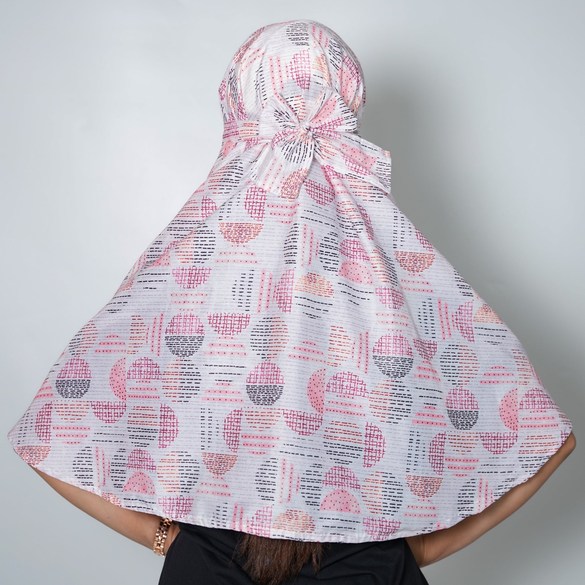Person wearing a patterned headscarf on a plain background