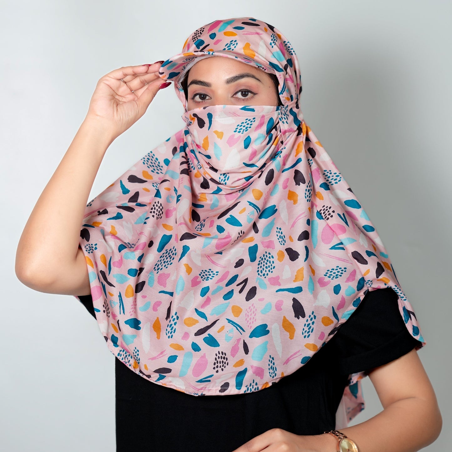 Woman wearing a colorful patterned cap scarf against a plain background