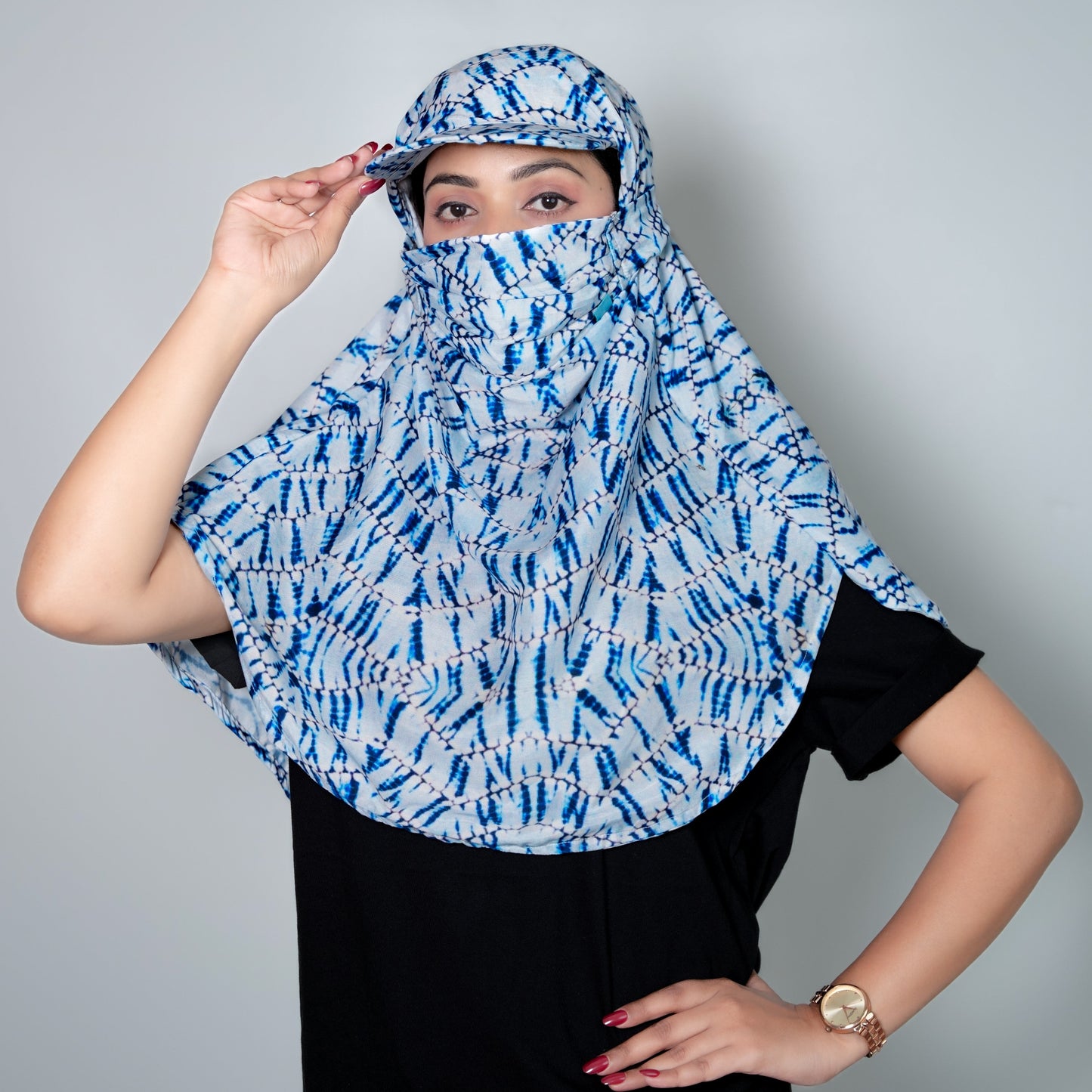 Woman wearing a blue and white patterned sun protection scarf against a gray background